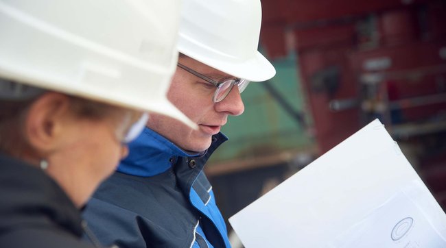 Two engineers looking at paper plan